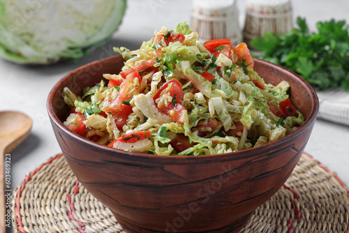 Salad with savoy cabbage, tomatoes and parsley in brown bowl on gray background