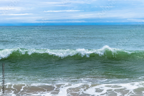 A panoramic view of an endless horizon where the deep blue ocean meets the sky, with white-capped waves rolling in the distance, evoking a sense of vastness and wonder..