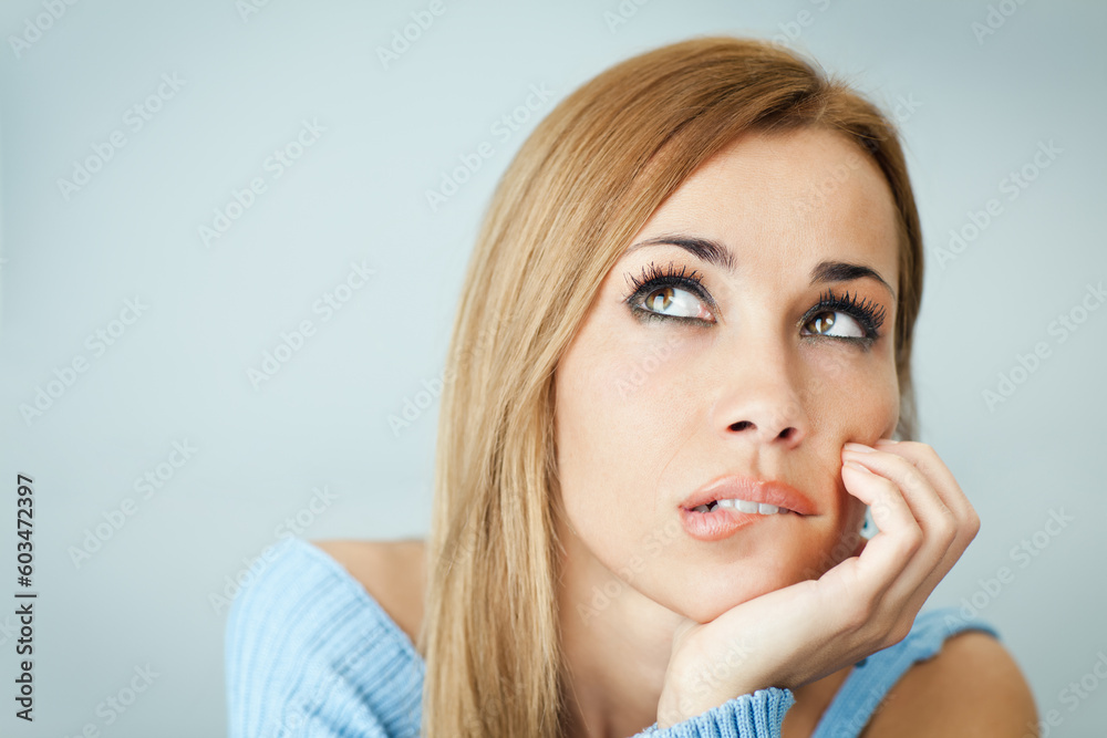 portrait of woman thinking and biting her lips, looking up with hand on cheek. Horizontal shape, Copy space portrait of woman thinking and biting her lips, looking up with hand on cheek. Horizontal shape, Copy space