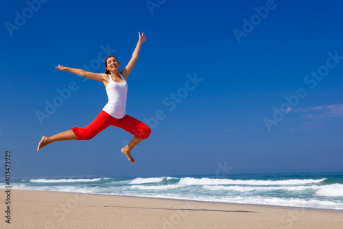 Beautiful young woman jumping on the beach