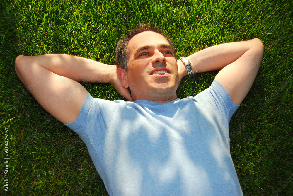A man lying on green grass relaxing A man lying on green grass relaxing
