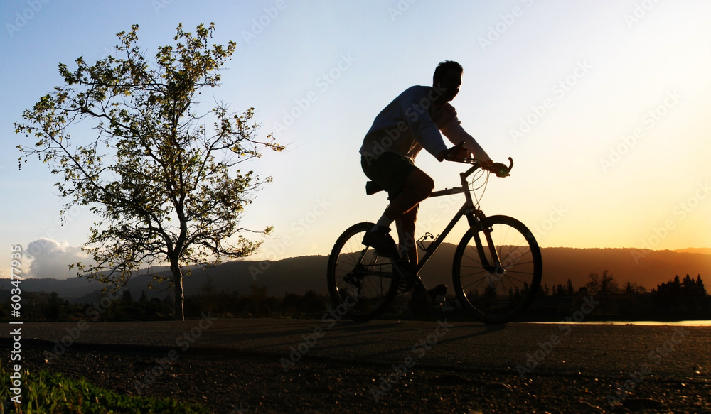 Fototapeta premium Man riding his bike at sunset