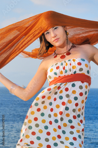 Fashion model holding oragne clouth against ocean background photo