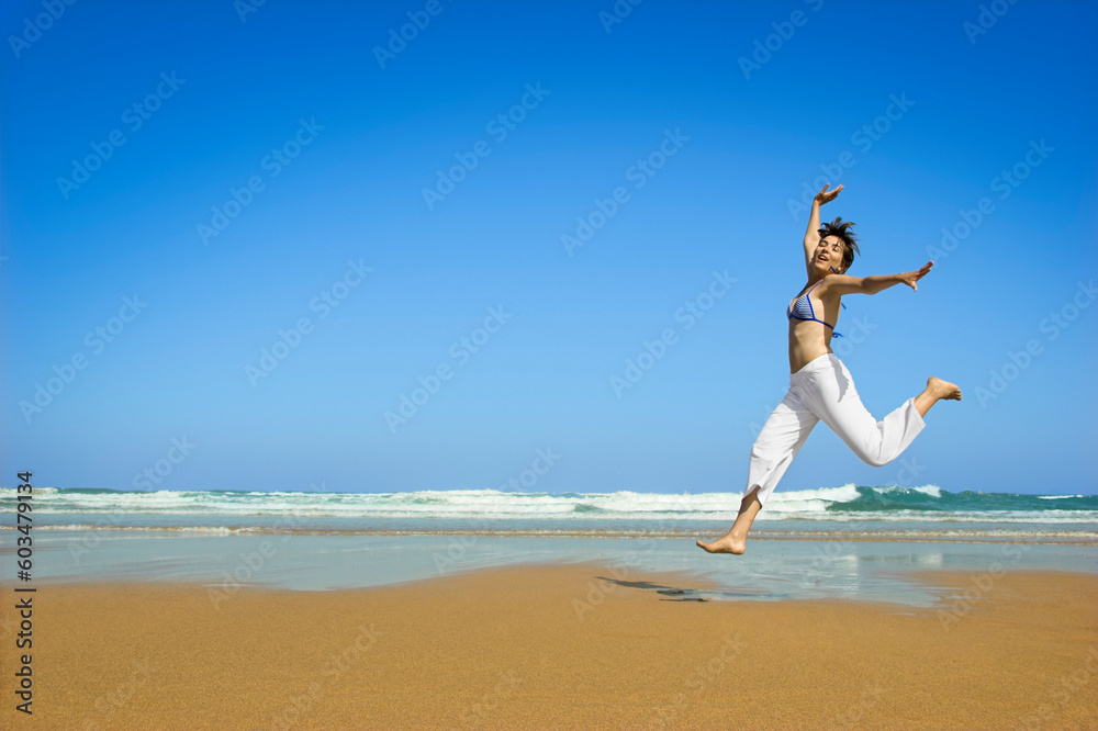 Beautiful young woman jumping on a beautiful beach Beautiful young woman jumping on a beautiful beach