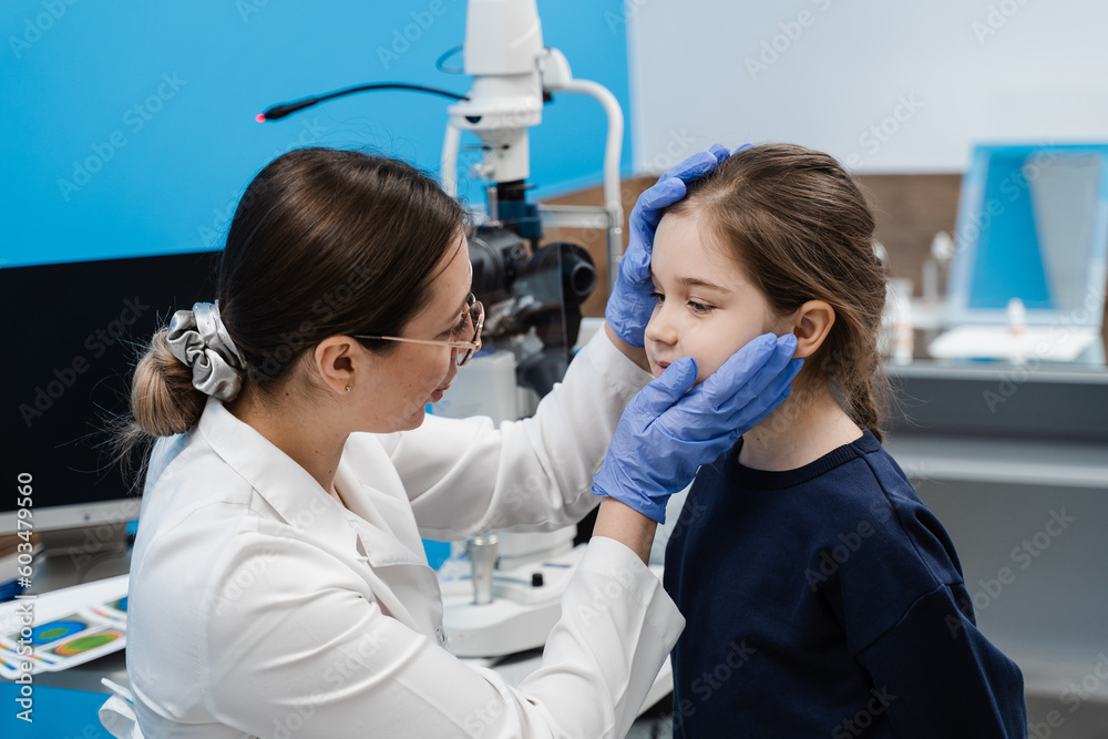 Pediatric ophthalmologist examines eyes and pupil of child. Consultation for children at ophthalmological clinic for treatment of eye inflammation and vision correction. Pediatric ophthalmologist examines eyes and pupil of child. Consultation for children at ophthalmological clinic for treatment of eye inflammation and vision correction.