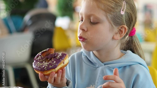 girl eating donut. Little girl eats delicious donuts with chocolate and berries. trend in food, sweets for kids. child with a donut in a cafe