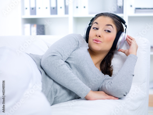Young woman laying on couch and listen to the music
