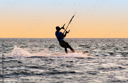 Silhouette of a kitesurfer on waves of a gulf