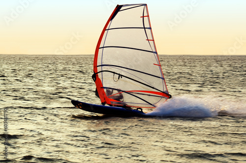 Silhouette of a windsurfer on a gulf, moving at great speed