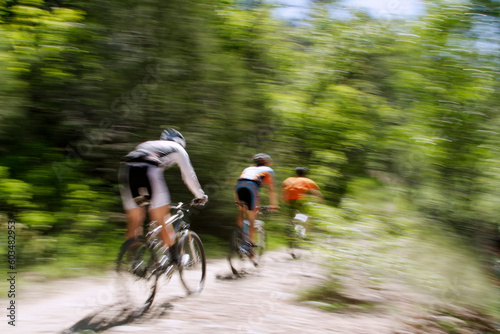Blurred panning shot of three mountain bikers riding through the forest.