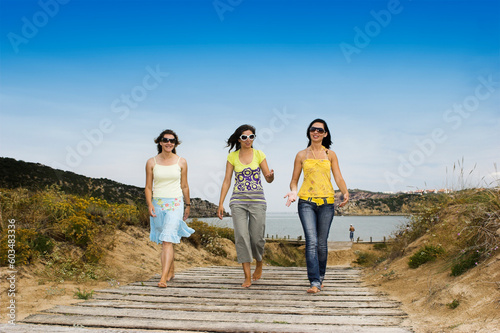 Three young girls walking with a beach on the background