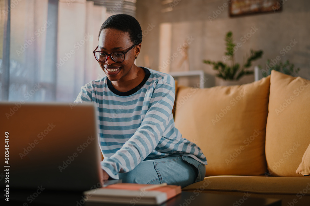 African american woman using laptop while sitting on a sofa at home African american woman using laptop while sitting on a sofa at home