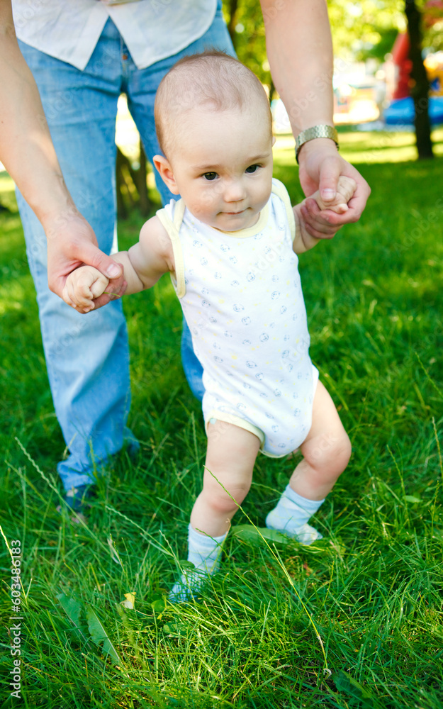 Baby boy walking in grass with fathers help Baby boy walking in grass with fathers help