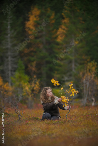Meditative portrait of a caucasian woman sitting next to a small yellow birch tree