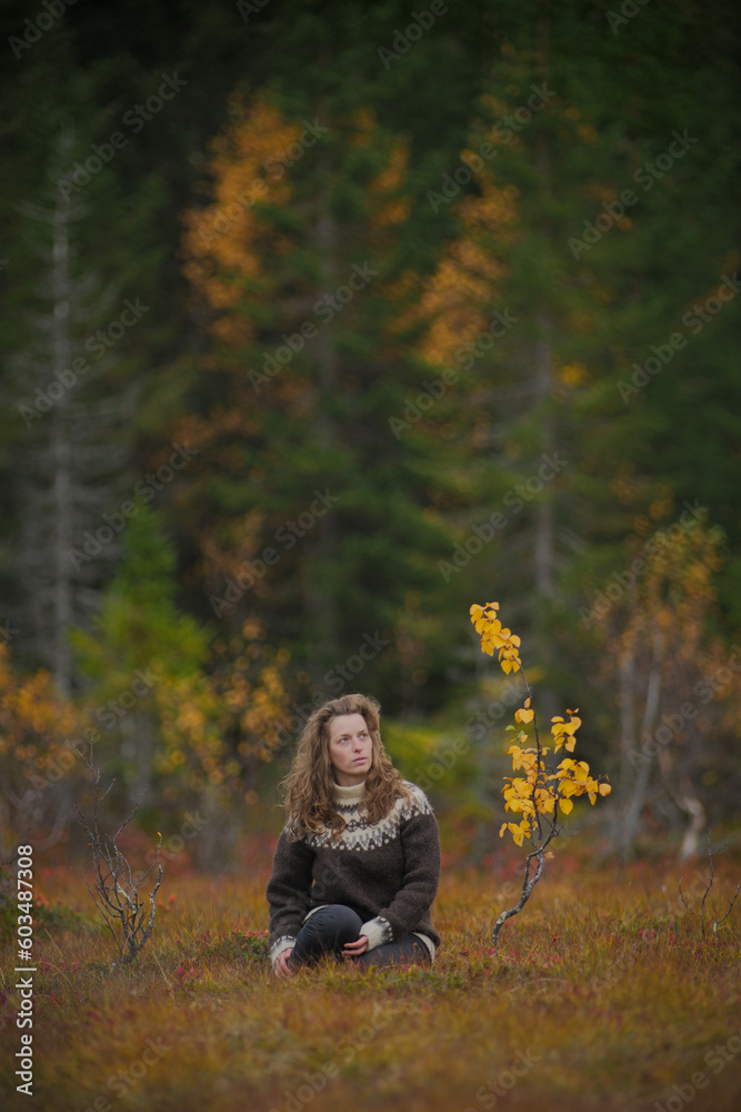 Meditative portrait of a caucasian woman sitting next to a small yellow birch tree