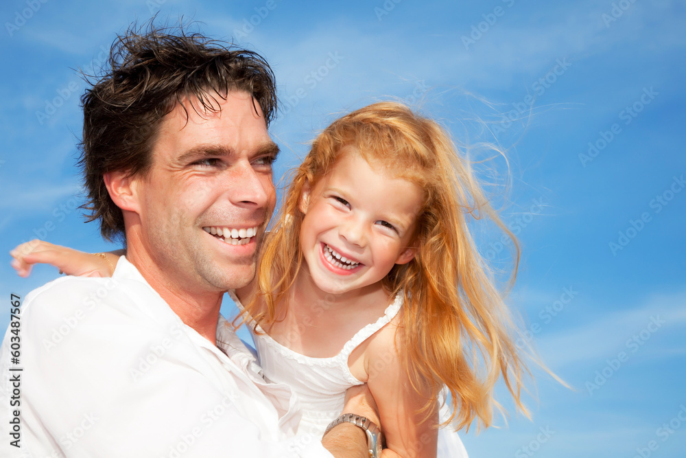 father and daughter having fun outdoors, dressed in white and with blue sky in background father and daughter having fun outdoors, dressed in white and with blue sky in background