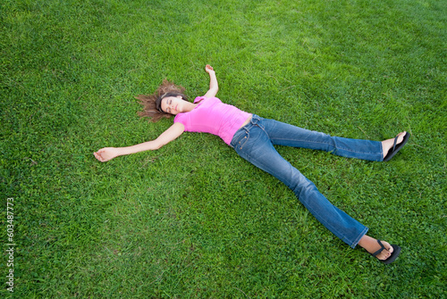 Young Woman relaxing lying on green grass