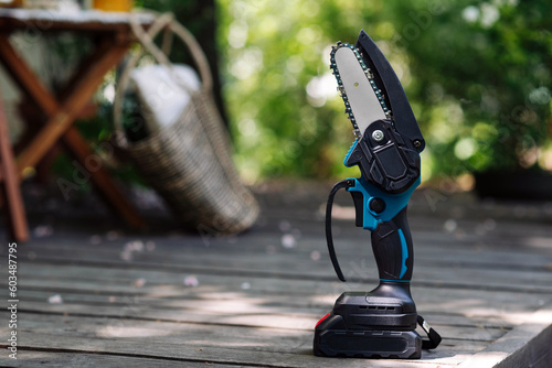 Fotografi mini portable electric chain saw on summer garden background