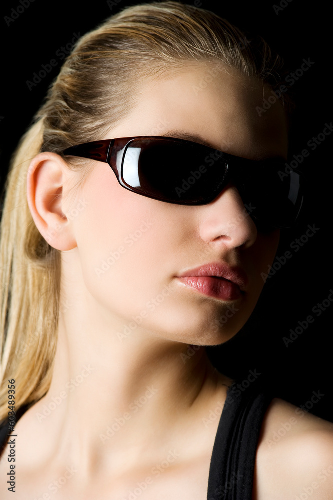studio shot with strong contrast of a girl on black with dark sunglasses studio shot with strong contrast of a girl on black with dark sunglasses