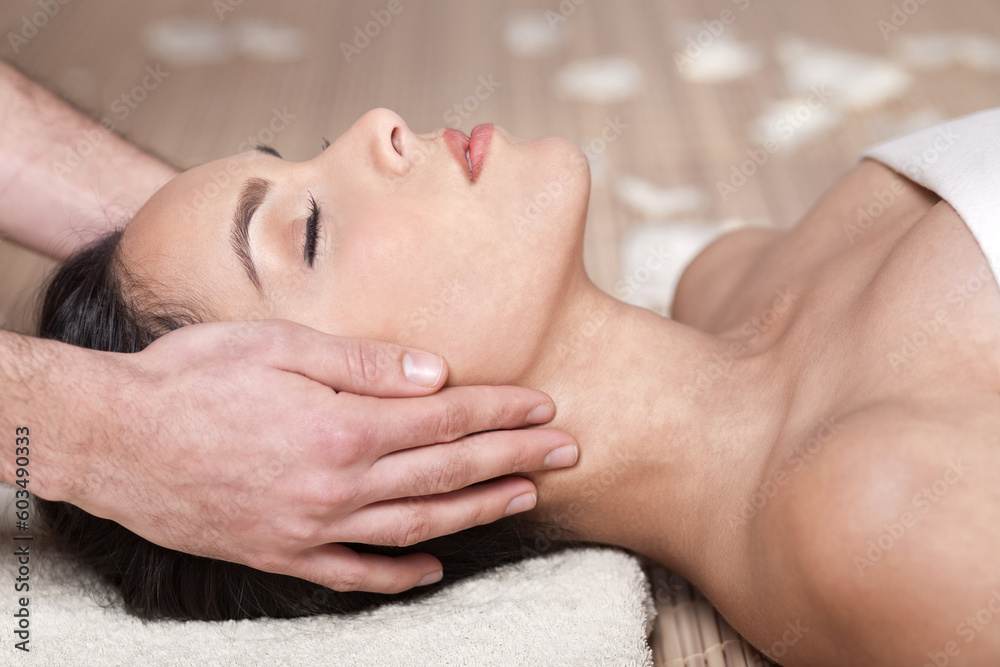 Happy woman receiving head massage over bamboo mat Happy woman receiving head massage over bamboo mat