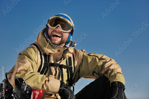 snowboarder relaxing and posing at sunny day on winter season with blue sky in background © Designpics