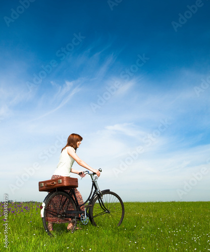 Happy young woman on a green meadow with a vintage bicycle © Designpics