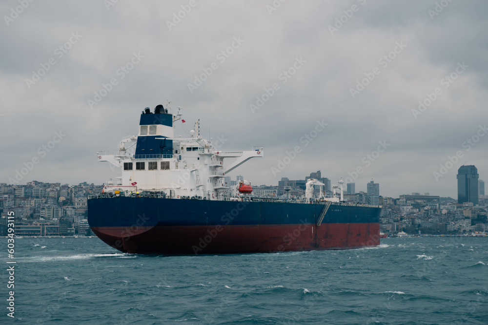 An impressive stock photo showcases a cargo ship navigating through Istanbul's Bosphorus Strait on a cloudy day, capturing the essence of maritime charm and the city's iconic skyline.