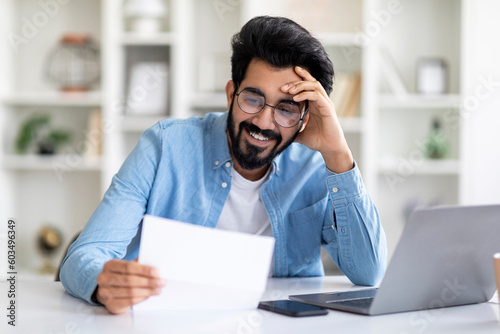 Young Indian Male Self-Entrepreneur Working With Papers At Desk In Home Office