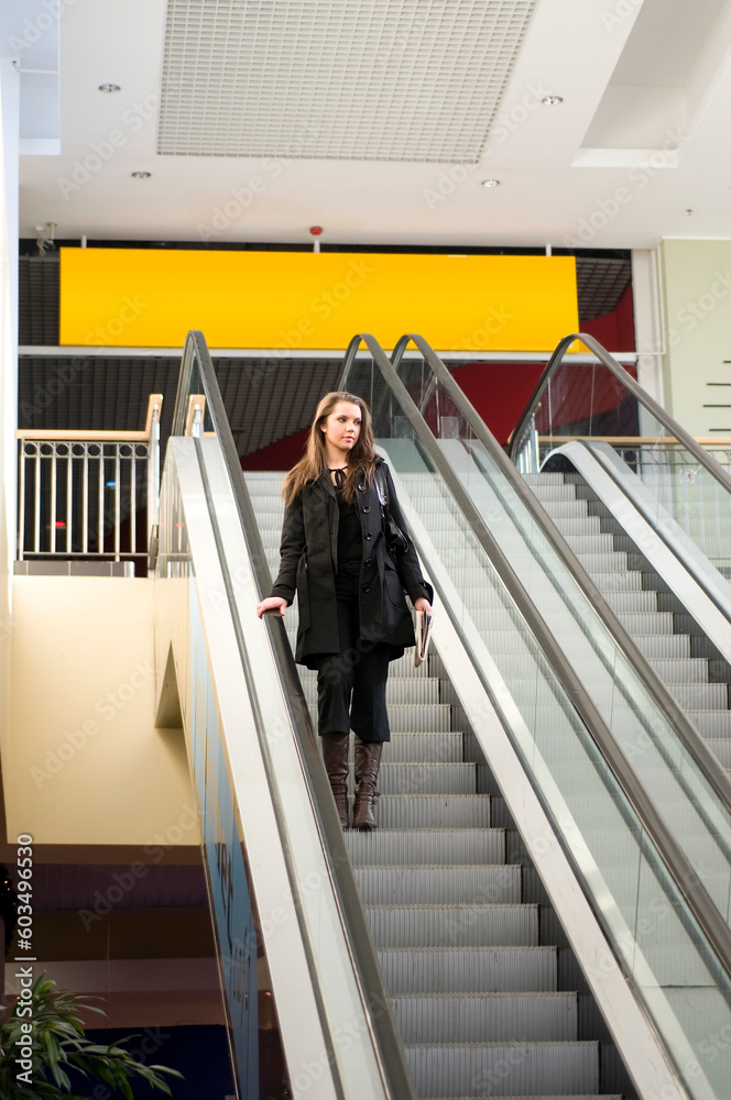 pretty brunette in black coat going down stair in commercial center pretty brunette in black coat going down stair in commercial center