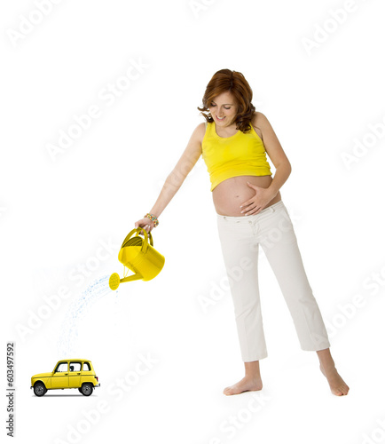 Beautiful pregnant woman watering a yellow car toy