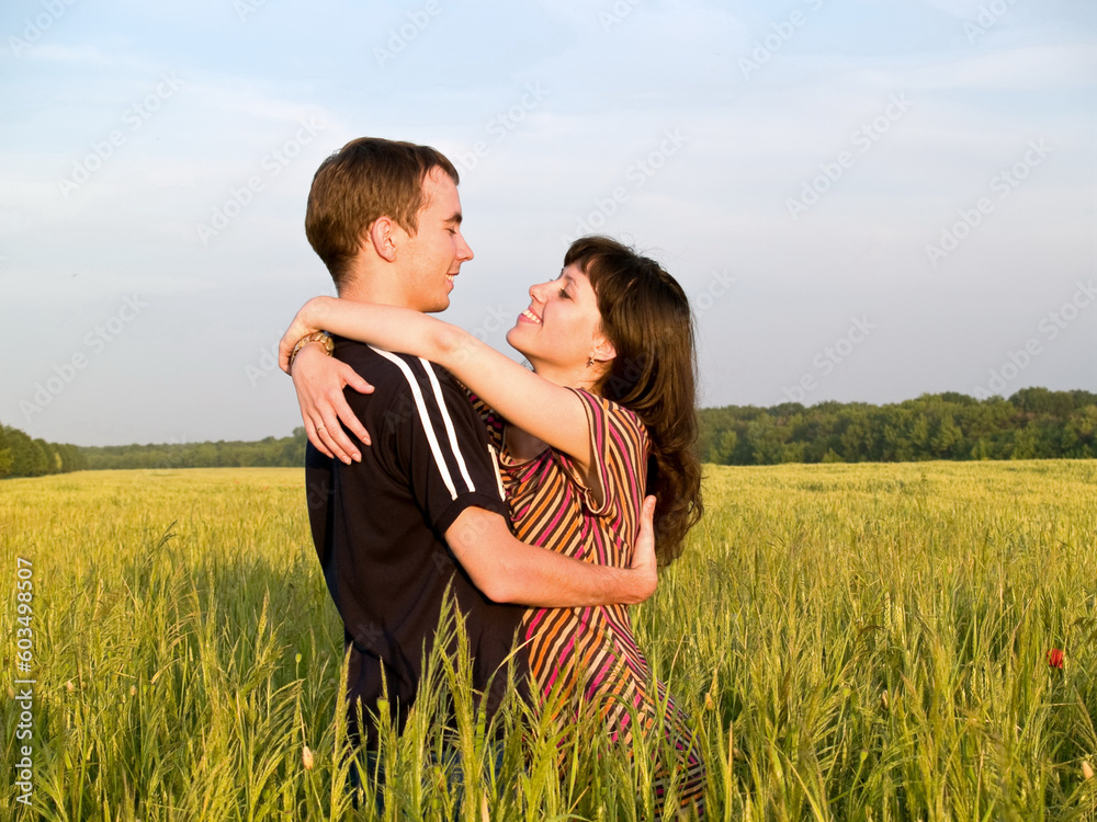 Teen couple embracing in field looking on each other Teen couple embracing in field looking on each other