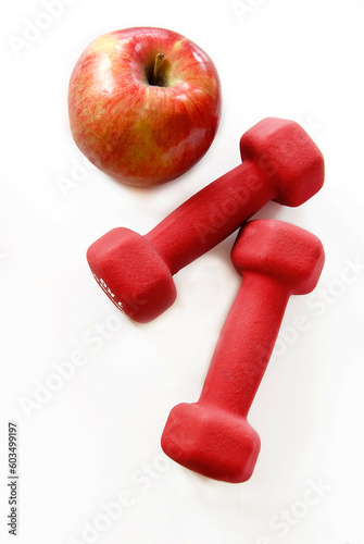 Photos two red dumbbells and red apple isolated on white