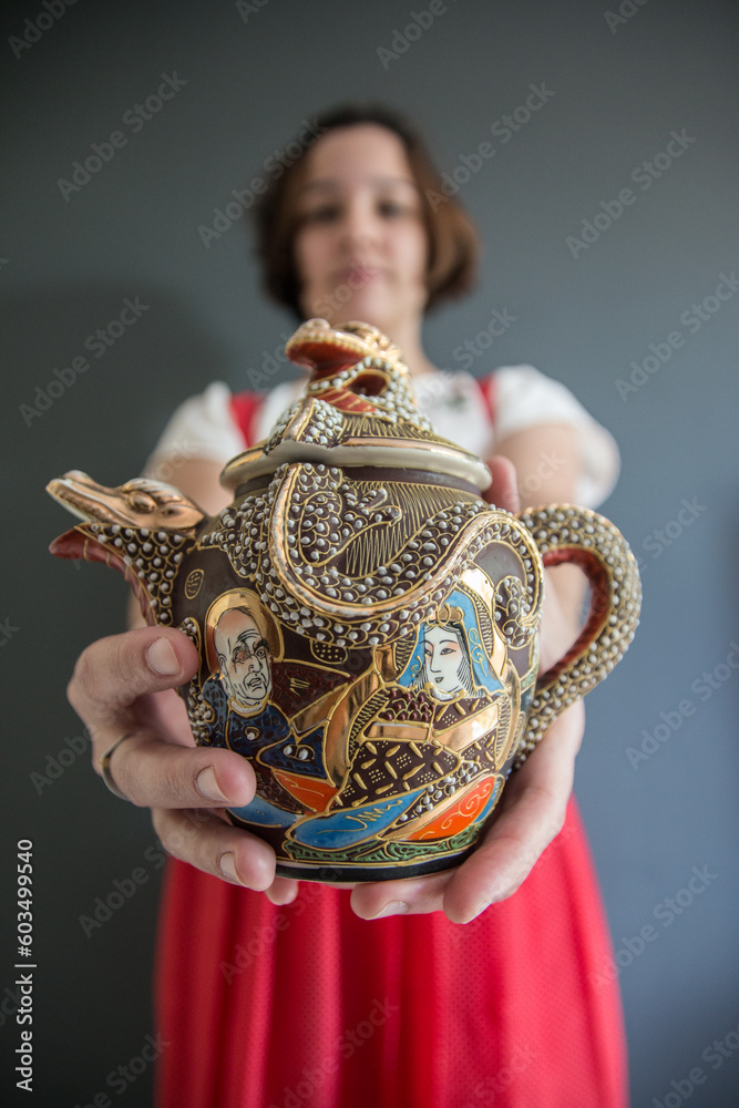 Mujer sosteniendo un jarrón japonés para servir té