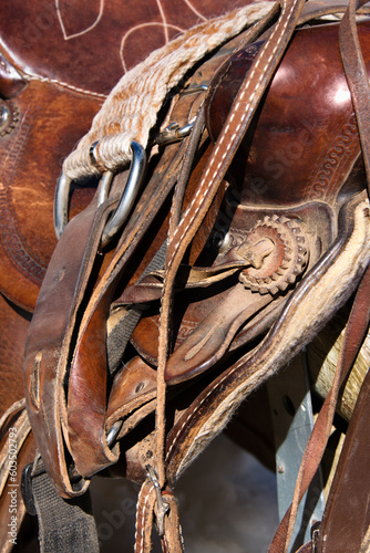 Detail of a western style horse saddle and cinch on a rail. Vertical shot. © Designpics
