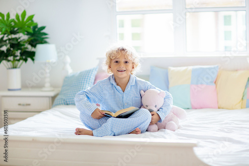 Child reading book in bed. Kids read in bedroom.