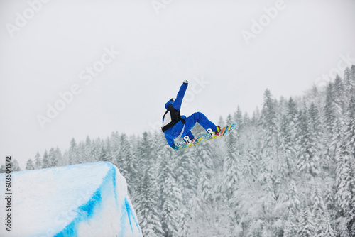 young boys jumping in air ind showing trick with snowboard at winter season