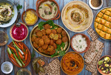 Mediterranean food spread with hummus, falafel, roasted pepper dip, yogurt sauce, crudites