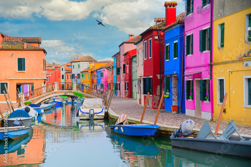 Colorful houses of Burano island. Multicolored buildings on fondamenta embankment of narrow water canal with fishing boats and stone bridge, Venice Province, Veneto Region, Italy. Burano postcard © lo-chef