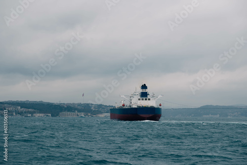 An impressive stock photo showcases a cargo ship navigating through Istanbul's Bosphorus Strait on a cloudy day, capturing the essence of maritime charm and the city's iconic skyline.