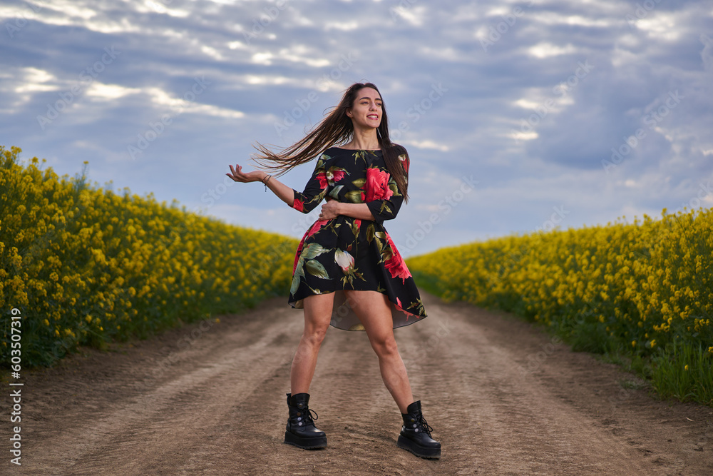 Obraz premium Beautiful latino woman in floral dress in a canola field