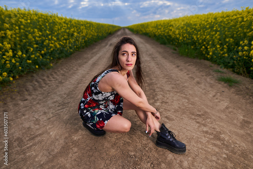 Beautiful latino woman in floral dress in a canola field