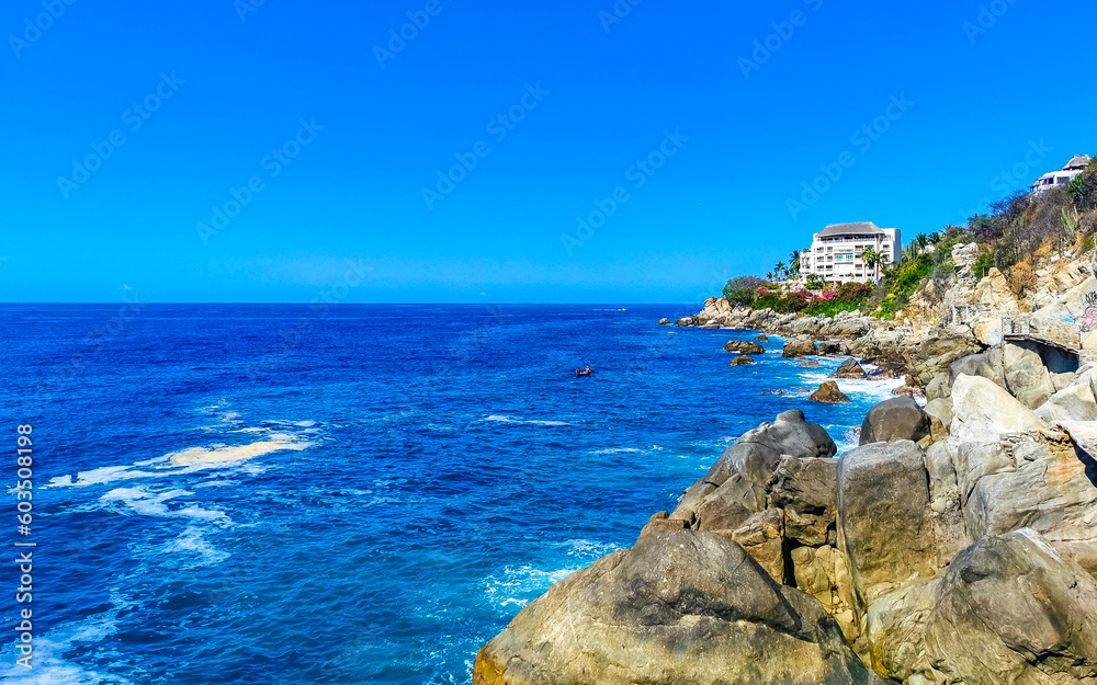 Surfer waves turquoise blue water rocks cliffs boulders Puerto Escondido.