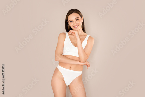 Beautiful young european woman posing on beige, wearing underwear
