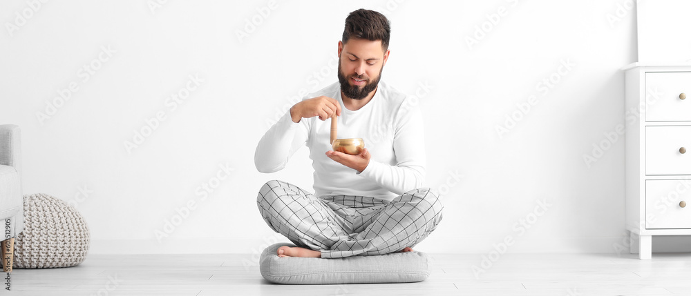 Man with Tibetan singing bowl meditating at home