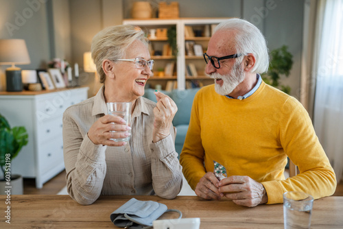 senior couple at home woman take medicine while her husband sit beside