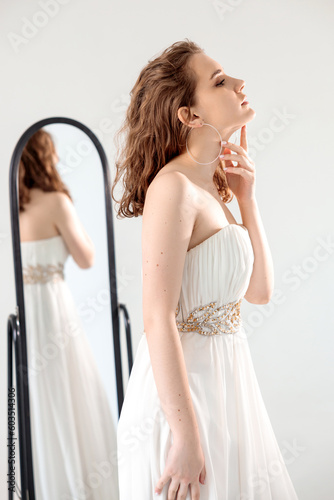 young girl in a white dress reflected in the mirror.on a white background