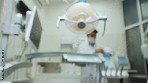 Brurred copy space video. Male dentist preparing for patient at clinic. A dentist wearing medical gown, gloves and white mask in his office, starts working with dental tools.Concept of healthy teeth photo