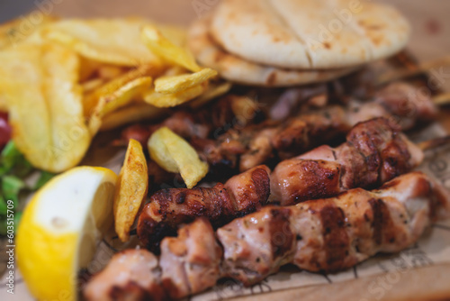 Fototapeta Naklejka Na Ścianę i Meble -  View of Souvlaki on a plate - traditional greek cuisine dish with grilled bbq chicken with french fries and tzatziki sauce served in a taverna cafe restaurant in the streets of Athens, Attica, Greece