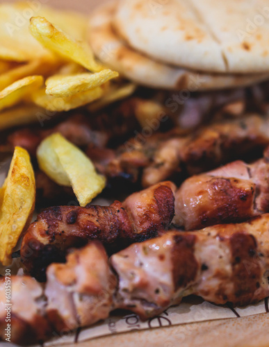 View of Souvlaki on a plate - traditional greek cuisine dish with grilled bbq chicken with french fries and tzatziki sauce served in a taverna cafe restaurant in the streets of Athens, Attica, Greece