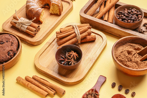 Composition with cinnamon sticks, powder, coffee beans, cake and cookies on yellow background